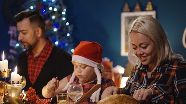 Child sitting between two adults at a festive dinner.