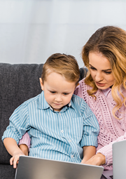 Mom teaching her son how to use a laptop.