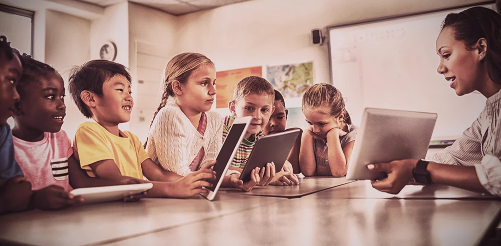 Teacher teaching computer safety around a table in school.