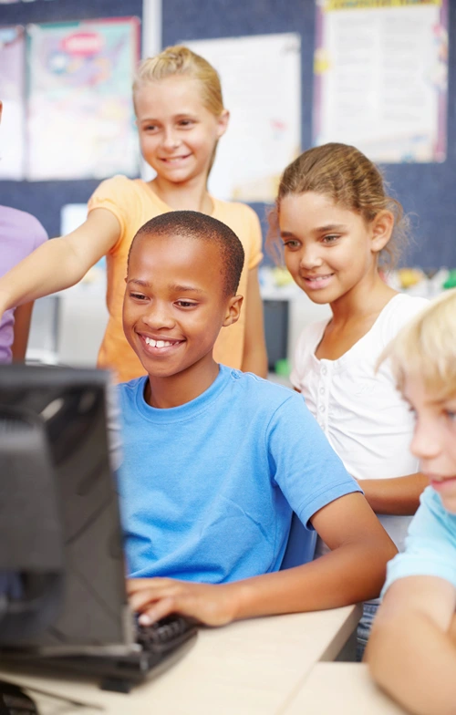 Kids at school gathered around a desktop computer for Safer Internet Day.