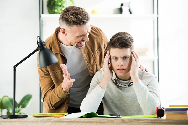 A man yelling at a teen boy.