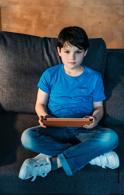 Boy sitting cross legged looking up from his laptop