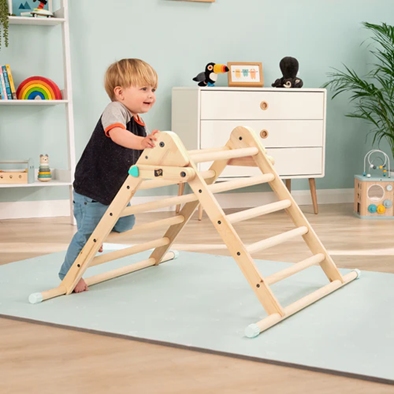 Young boy climbing up wooden stepping triangle.