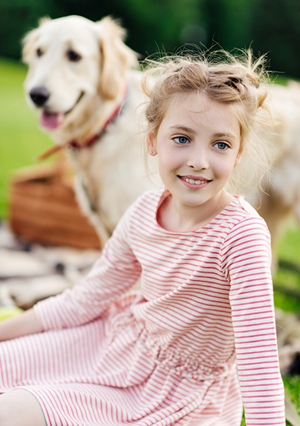 Girl sitting in grassy park with her large dog.