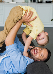 Dad playfully holding his young son upside down