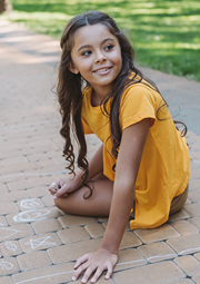 Girl drawing on sideway with chalk, then looks away.