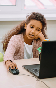 Girl engaged in playing game with mouse on her laptop.