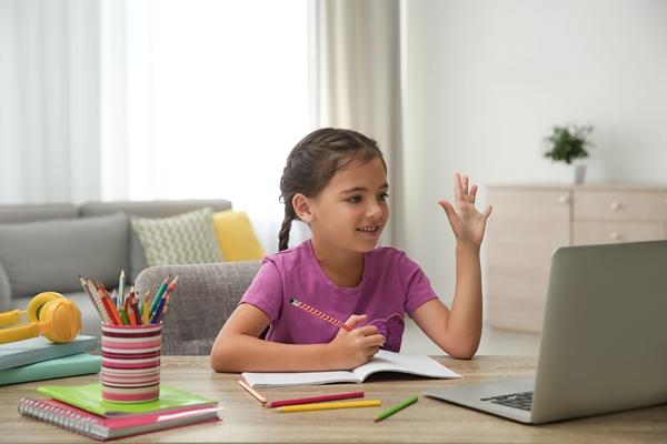 Gile taking online class and waving at teacher on the computer.