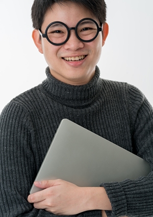 Korean man with big smile holding a laptop in his hand.