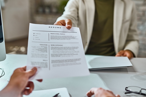 Job applicant hands resume across a desk in a job interview.