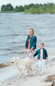 Mom and Daughter Walking Dog on the Beach of a Lake