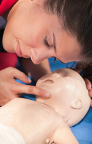 Women in training practicing CPR on infant manikin.