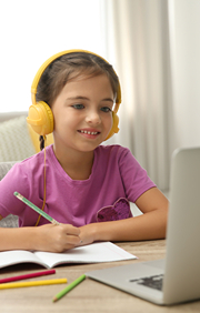 Girl with headphones on with pencil and pass taking online class.