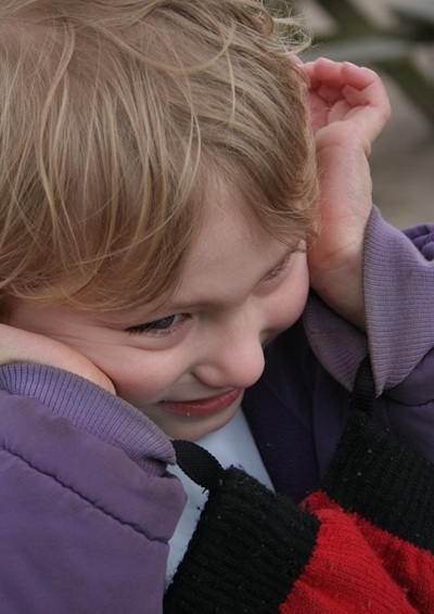 Autistic boy covering his ears.