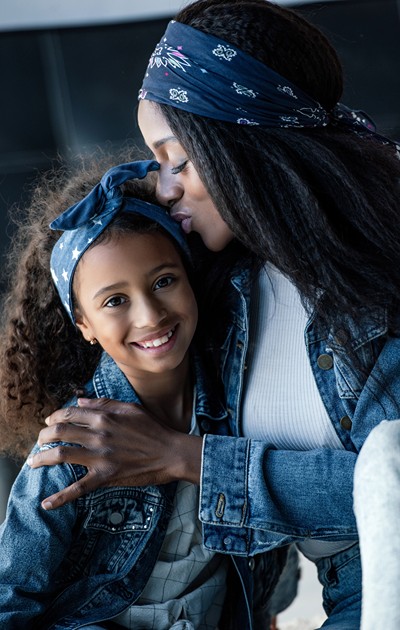 Black woman holder her smiling tween daughter.