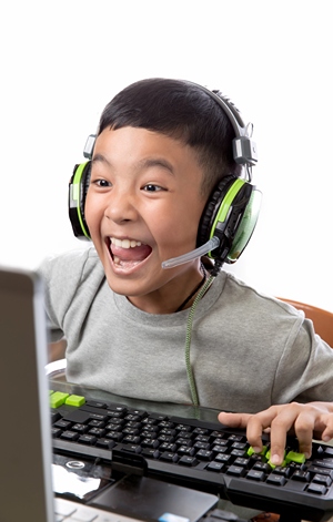 Excited boy playing computer game with headset.