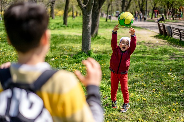 Little boy throwing large ball to big brother.