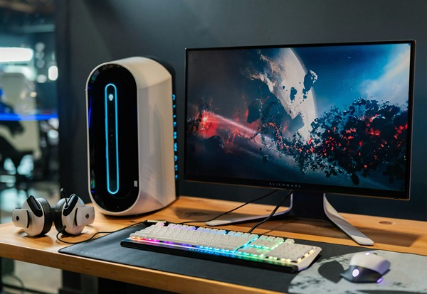 Desk with computer, colorful keyboard, speaker and headphones.