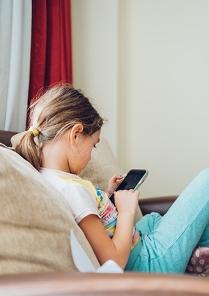 Little girl on couch looking at phone.