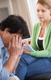 Man holding hands over his face in counseling session with therapist.