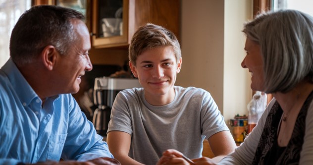 Parents and son having a light hearted conversation at the table.