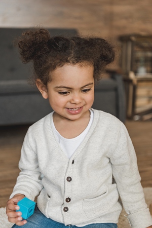 Smiling child holding a block and playing