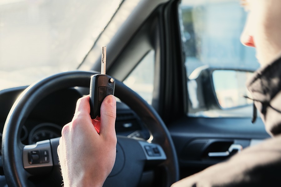 Male teenager holding up keys in car, as if about to drive alone for the first time.