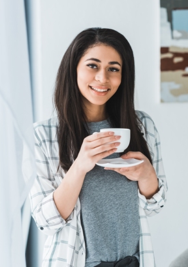 African American woman smiling will holding coffee cup.