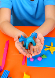 Hands of a boy holding up a dinosaur sculpture he made.