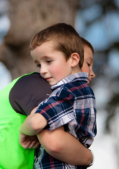 Older boy hugging his brother with special need.