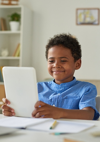 Boy holding tablet and smiling.