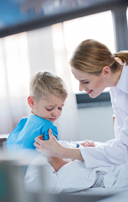 Pediatrician gives boy a needle at her clinic.