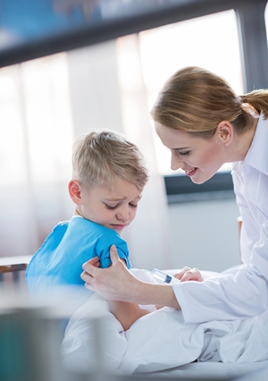 Pediatrician gives boy a needle at her clinic.