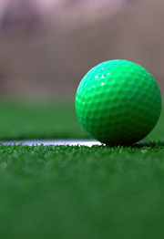 A golf ball teeters on the green right next to the hole.