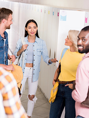 Group of college students conversing by lockers in hallway.