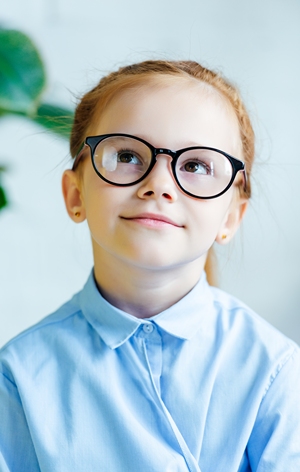 Girl with glasses in school uniform thoughtfully looking upward.