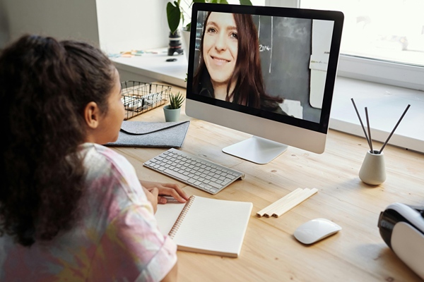 Teacher on computer screen smiling at child at home.