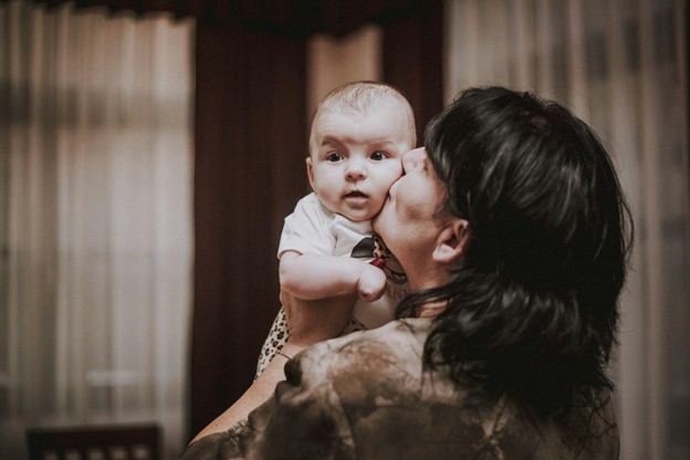 Mom at home holding her baby up to her face.