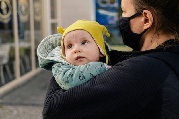 View over mother's shoulder as her baby looks off into distance.