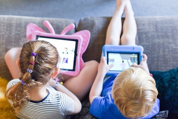 Shot of over the shoulders of boy and girl playing games on tablets.