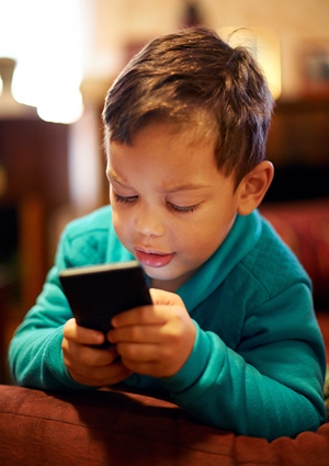 A young boy tightly holding smart while clicking screen with his thumbs.