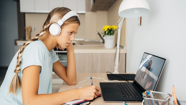  Female student taking online class with headphones on.