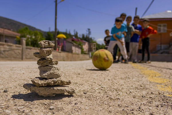 A group of boys blurred in the background playing with a ball outside.