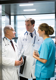 Two doctors speaking with a surgeon in hospital.