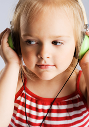 Little girl listening intently to headphones and hold both sides with her hands.