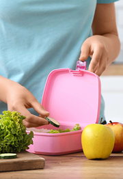 Mom in kitchen packing lunch box for kids school