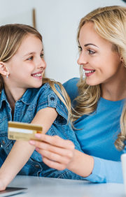 Daughter sits on mom's lap as she holds up a credit card.