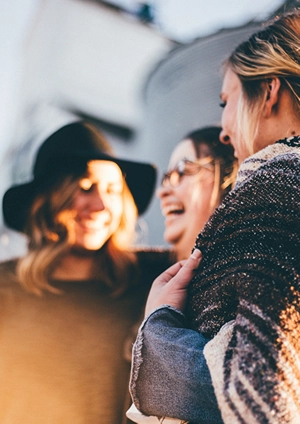 College aged women talking and laughing outdoors.