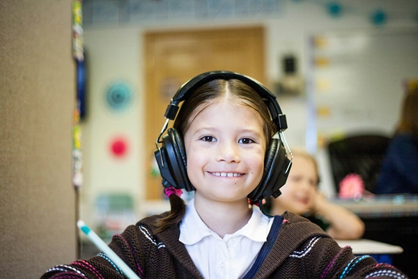 Tween Girl in Classroom with Headphones on.