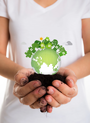 Young girl holding globe in dirt with tress sprouting out on top.